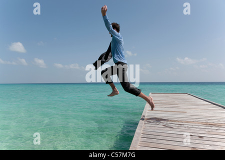 Businessman jumping dal jetty in mare Foto Stock