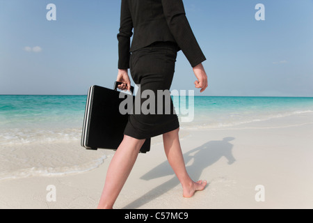 Imprenditrice camminando sulla spiaggia tropicale Foto Stock