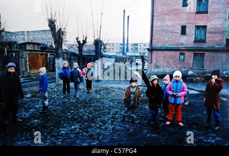 Bambini sotto forma di Transilvania città mineraria di Petrila in Romania giocano allegramente nel fango e immondizia disseminata strade 1994 Foto Stock