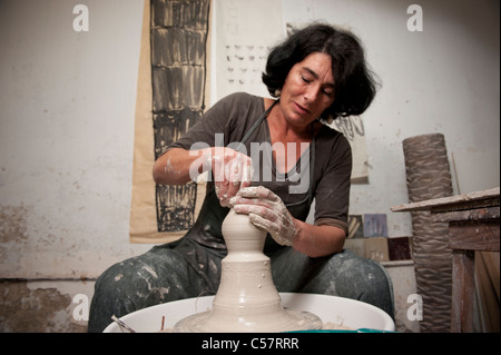 Ceramista femmina usando un tornio del vasaio al lavoro su un pezzo di ceramica nel suo workshop, Barcellona, Spagna Foto Stock