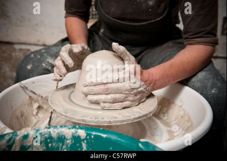 Ceramista femmina usando un tornio del vasaio al lavoro su un pezzo di ceramica nel suo workshop, Barcellona, Spagna Foto Stock