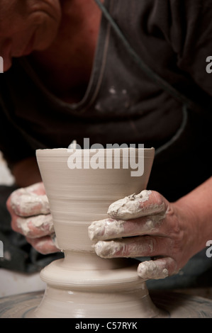 Ceramista femmina usando un tornio del vasaio al lavoro su un pezzo di ceramica nel suo workshop, Barcellona, Spagna Foto Stock