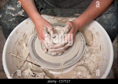 Ceramista femmina usando un tornio del vasaio al lavoro su un pezzo di ceramica nel suo workshop, Barcellona, Spagna Foto Stock