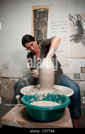 Ceramista femmina usando un tornio del vasaio al lavoro su un pezzo di ceramica nel suo workshop, Barcellona, Spagna Foto Stock