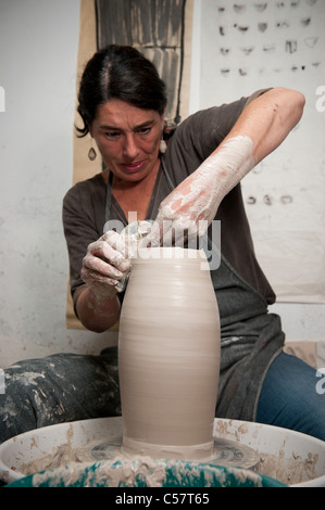 Ceramista femmina usando un tornio del vasaio al lavoro su un pezzo di ceramica nel suo workshop, Barcellona, Spagna Foto Stock