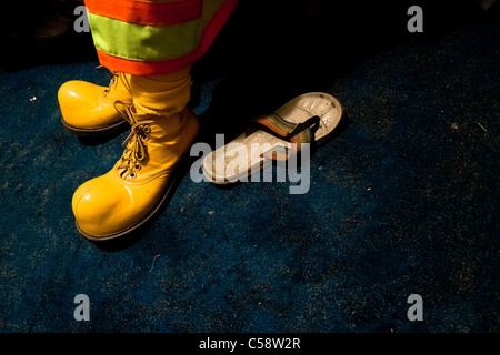 Un colombiano uomo indossa il giallo clown scarpe prima di uno spettacolo al circo anny, una conduzione familiare circus vagare in Ecuador. Foto Stock