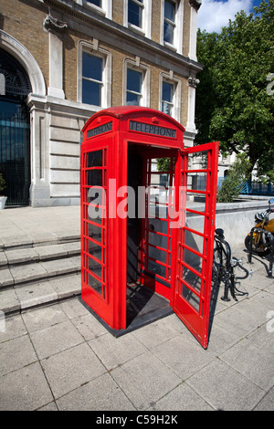 Il vecchio telefono rosso cabina con porta aperta a Londra Foto Stock