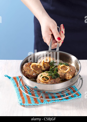 Giovane donna tenendo la coppa con polpettine di carne e anelli di cipolla fritti Foto Stock