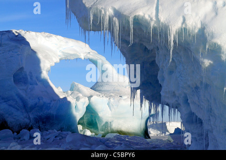 Blue sky attraverso il foro nella iceberg arco incastonato nel mare di ghiaccio nel Mare di Ross Antartide Foto Stock