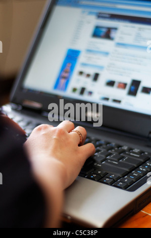 Oltre la spalla shot femminile di digitazione su computer portatile, celtica anello sulla mano destra anello dito. Foto Stock