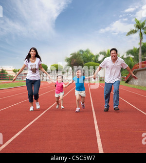 Felice famiglia asiatica correndo insieme sulla pista dello Stadio Foto Stock