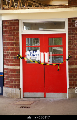 Cartello con vernice bagnata sulla porta rossa e cordonato con nastro adesivo alla piattaforma della stazione ferroviaria di Brockenhurst, New Forest, Hampshire UK a giugno Foto Stock