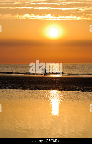 Padre e figlio facendo una passeggiata sulla spiaggia al tramonto, Wangerooge, Germania. Foto Stock