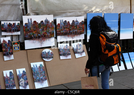 Ragazza guardando i dipinti ad olio di scene della città per la vendita al fianco di Green Park e Piccadilly, Londra, Inghilterra Foto Stock