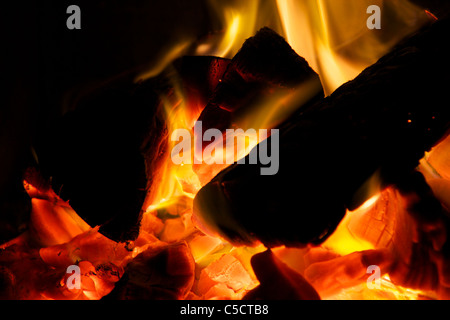 Spaccare la legna brucia in carboni caldi con fiamme di colore ambra Foto Stock