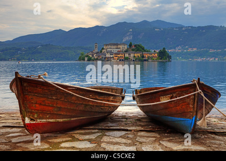 L'isola di San Giulio sul Lago d'Orta con due vecchie barche di legno in primo piano Foto Stock