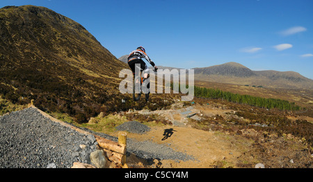Una discesa con la mountain biker vola via un salto al Glencoe Mountain Resort nelle Highlands della Scozia Foto Stock
