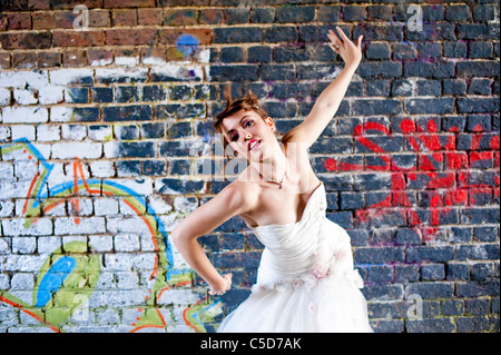 Sposa pone contro il muro di graffiti in abito da sposa Foto Stock