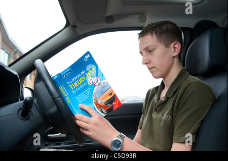 Ragazzo adolescente studiando la gazzetta dsa prova teorica manuale prima di una lezione di guida. Foto Stock