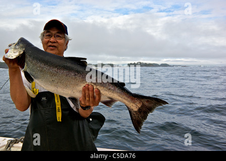 Asian holding maschio grande sport catturato il Salmone Chinook Suono Kyuquot BC Foto Stock