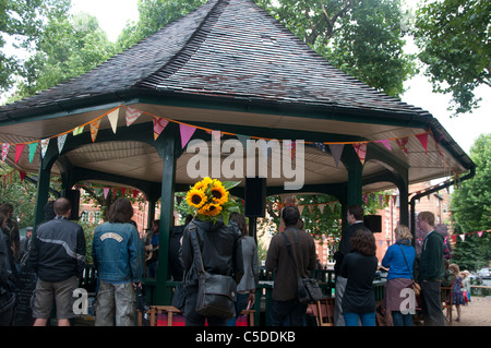 Arnold Circus Shoreditch, Londra Luglio 2011. Uomo con mazzo di girasoli nella parte anteriore del palco per spettacoli. Foto Stock