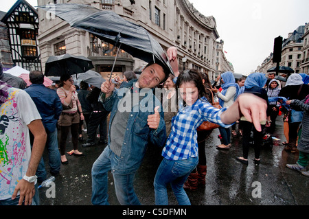 Le persone sotto gli ombrelloni in strada a Rainy day a Londra Foto Stock