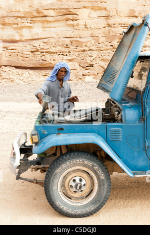 Muzeina uomo beduino il riempimento di acqua nel sistema di raffreddamento della sua jeep - Wadi Arada deserto - Penisola del Sinai, Egitto Foto Stock