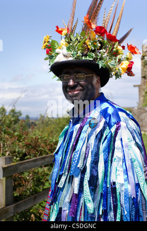 Ballerini Exmoor Border Morris, fronte nero, con lunghi stracci strappati, vestiti fatti di grandi bulloni di materiale blu e bianco, vestiti e celebrazione di ballo, evento all'aperto, ballerina di strada, ballerini in costume, stracci a scorrimento lungo, cloggies, esecuzione, spettacolo di artisti folk, musicisti multicolore, popolare, Spettacolo tradizionale al Tutbury Castle Weekend di Dance Derbyshire, Regno Unito. Foto Stock