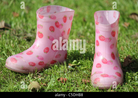 Due piccoli Fragola Rosa stivali di gomma in erba verde Foto Stock