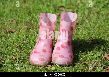 Due piccoli Fragola Rosa stivali di gomma in erba verde Foto Stock