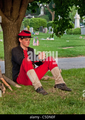 Una guerra civile reenactor indossando periodo uniforme per commemorare il Memorial Day è giustapposto con tombe nel cimitero Green-Wood,NYC. Foto Stock