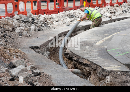 Workman tubazione di posa di nuovi cavi a banda larga, London, England, Regno Unito Foto Stock