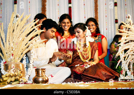 Un Ritratto Dettagliato del groom collocando un anello di nozze su la sposa del dito durante il loro matrimonio induista rituale Foto Stock