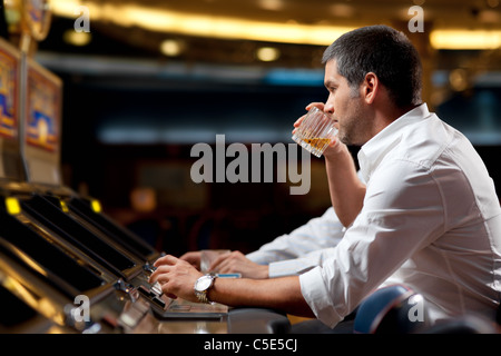 Uomo bello beeing concentrata nel giocare alle slot machine Foto Stock