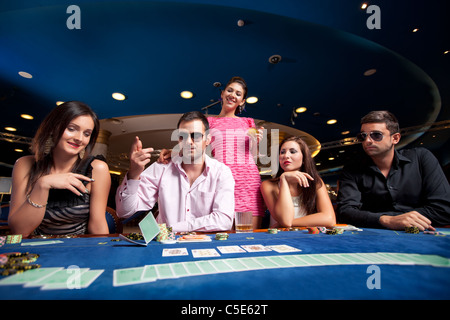 L'uomo gettando con le sue carte da poker mentre altri giocatori guardare lui Foto Stock