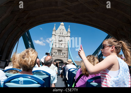 I turisti su open top double decker il Tour Originale di Londra autobus attraversando il Tower Bridge di Londra, Regno Unito Foto Stock