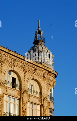 Particolare di una facciata e cupola dell'edificio Belle Epoque a Narbonne, in Francia, con una mezza luna visibile nel cielo serale. Foto Stock