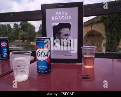 Le lattine di 1664 Kronenbourg birra chiara con un menu, su un tavolo in uno snack bar presso il fiume Dordogna in Castlenaud, Francia Foto Stock