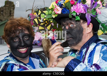 Ballerini Exmoor Border Morris, fronte nero, con lunghi stracci lacerati, abiti fatti di vistelli di materiale blu e bianco, vestiti e feste danzanti, eventi all'aperto, ballerini di strada, ballerini in costume, stracci lunghi, Slogan, esecuzione, esecuzione di artisti folk, musicisti multicolore, popolare, esecuzione di intrattenimento tradizionale campagna al Tutbury Castle Weekend di Dance Derbyshire, Regno Unito. Foto Stock