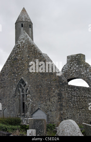 Kilmacduagh Monastero, nella contea di Galway, Irlanda. A 34 metri (112 piedi), la torre rotonda è il più alto in Irlanda. Foto Stock