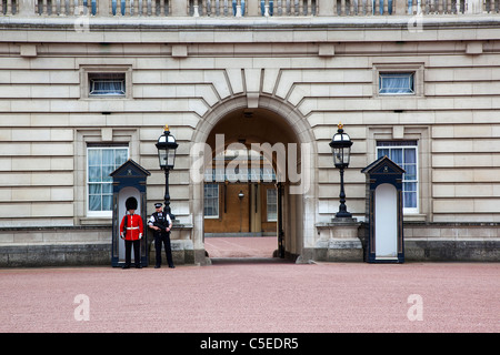 Inghilterra, London, Westminster, Buckingham Palace esterno con entrambe le regine della Guardia e la Metropolitan Police ufficiali armati. Foto Stock