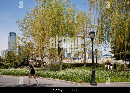 Runner e Walkers, Esplanade in Battery Park City, New Jersey grattacieli in background, NYC Foto Stock