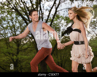 Licenza disponibile all'indirizzo MaximImages.com - giovane felice coppia romantica che corre insieme tenendosi per mano Foto Stock