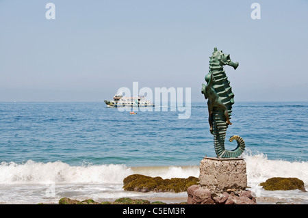 Focus su Los Muertos Beach cavalluccio scultura con un kayak e barca di partito in background su Banderas Bay, Messico. Foto Stock