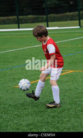 Giovani calciatori in controllo di palla su un Astra passo del fondo erboso Foto Stock