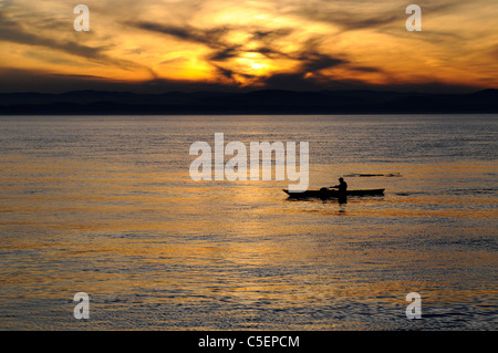 Lone uomo pagaie kayak Puget Sound San Juan Island al tramonto Foto Stock