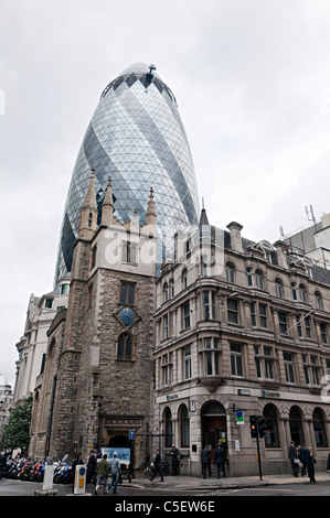 Il gherkin ufficio edificio disegnato da Sir Norman Foster nella città di Londra con St Andrew undershaft chiesa nella parte anteriore Foto Stock