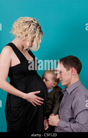 Il Toddler baciando la sua gravidanza madre di ventre Foto Stock