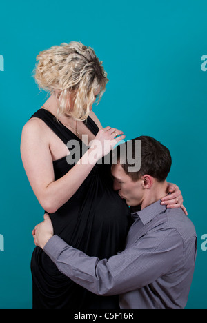 Uomo di baciare la sua gravidanza della donna del ventre Foto Stock