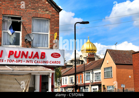 La cupola dorata del tempio Sikh si affaccia sui tetti delle case residenziali di Southall con un negozio d'angolo in primo piano West London Inghilterra Regno Unito Foto Stock
